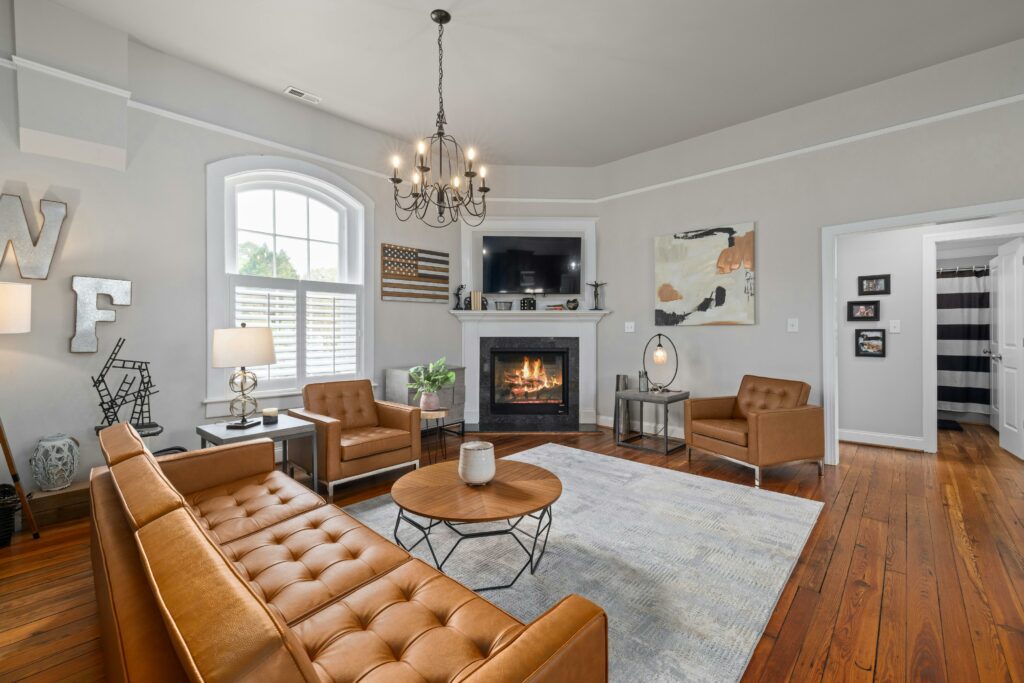 Cozy living room with leather chairs, white carpet on wooden floors and a fireplace.