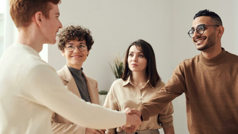 Three people shaking hands in an office: a professional greeting between colleagues.