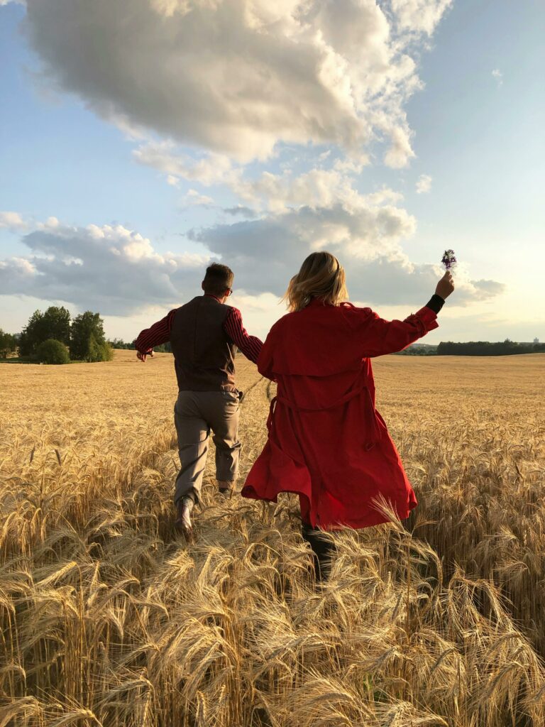 Happy couple walking hand in hand through a beautiful field.