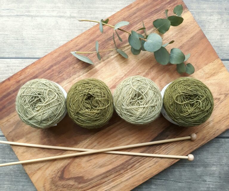 Yarn balls and knitting needles on wooden cutting board