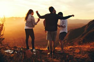 Three friends on a hill, arms outstretched, feeling the breeze